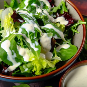 A bowl of fresh salad greens drizzled with a cream